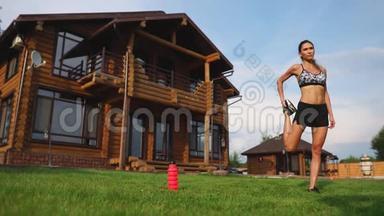 一位身材苗条、穿着运动服的美女正准备在家附近的草坪上开始训练